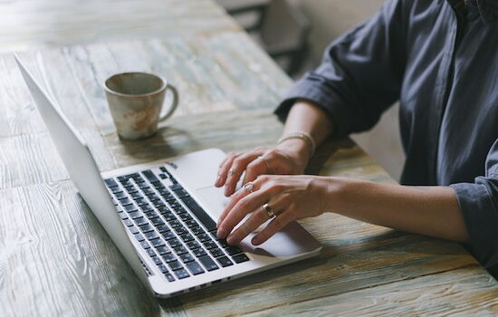 Eine Frau sitzt am Laptop und prüft eine Website auf ihre Rechtssicherheit.