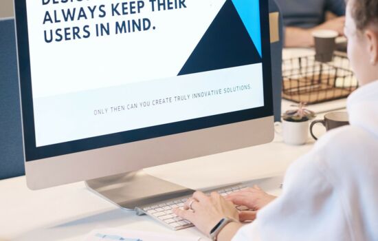 UX Designerin vor einem Monitor mit der Aufschrift "Designers schould always keep their users in mind.".